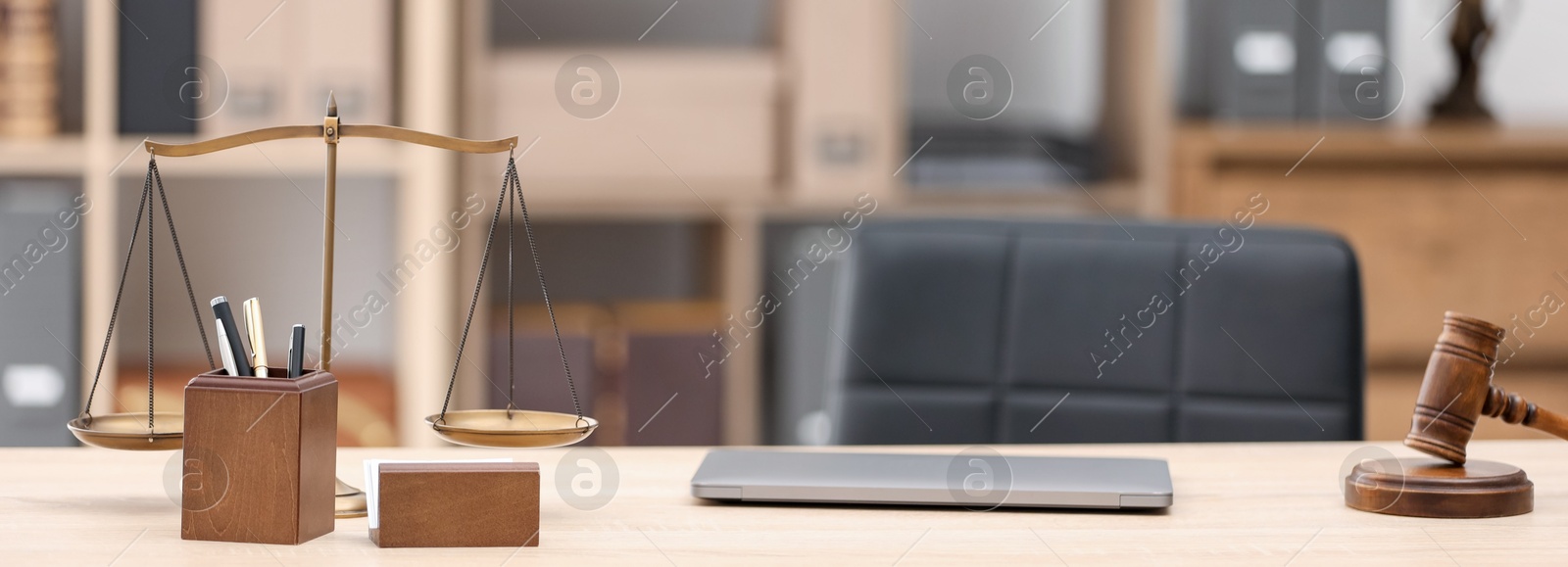 Judge's gavel, scales, laptop and stationery on wooden table in office Photo of Judge's gavel, scales, laptop and stationery on wooden table in office