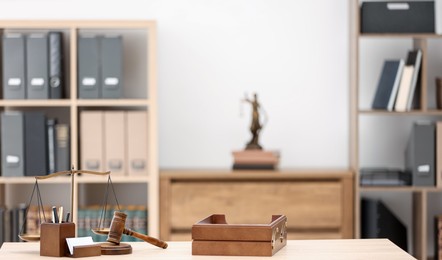 Photo of Judge's gavel, scales, stationery and document tray on table in office