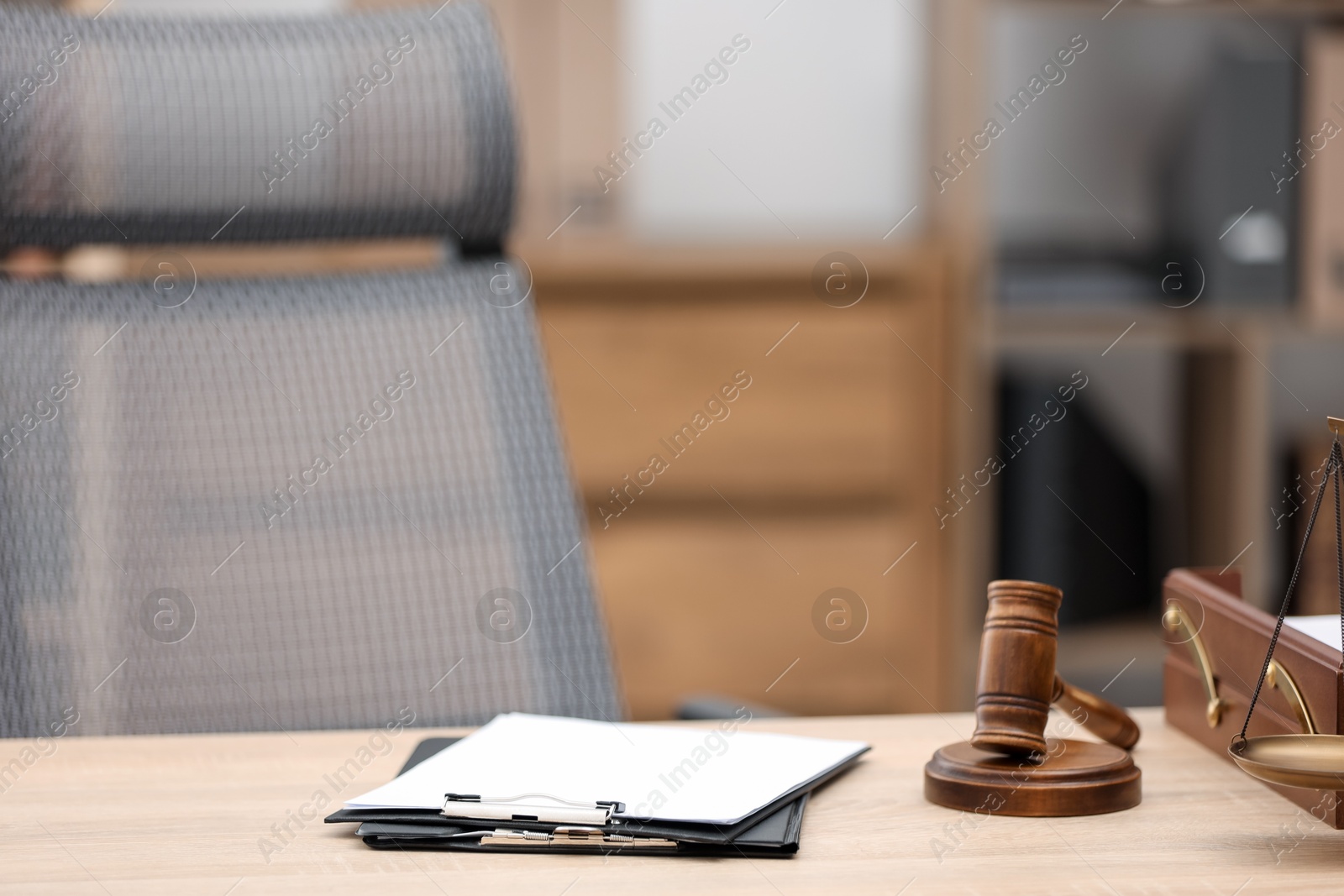 Judge's gavel, clipboards and scales on wooden table in office Photo of Judge's gavel, clipboards and scales on wooden table in office