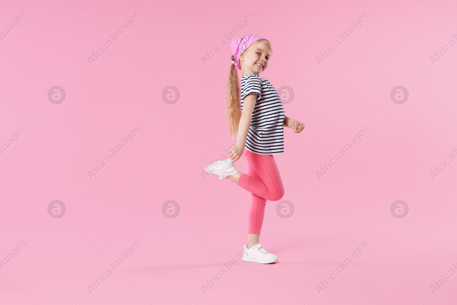 Cute little girl dancing on pink background Photo of Cute little girl dancing on pink background