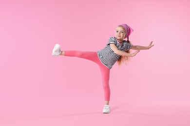 Photo of Cute little girl dancing on pink background