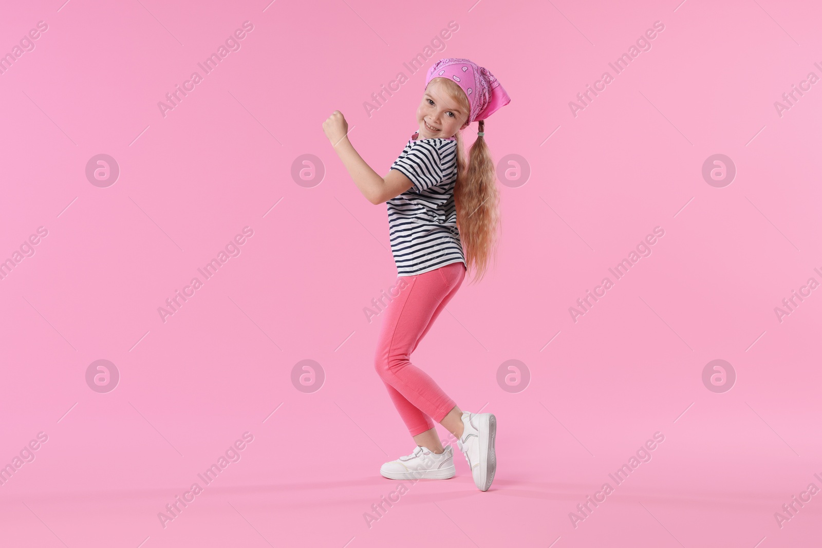 Cute little girl dancing on pink background Photo of Cute little girl dancing on pink background