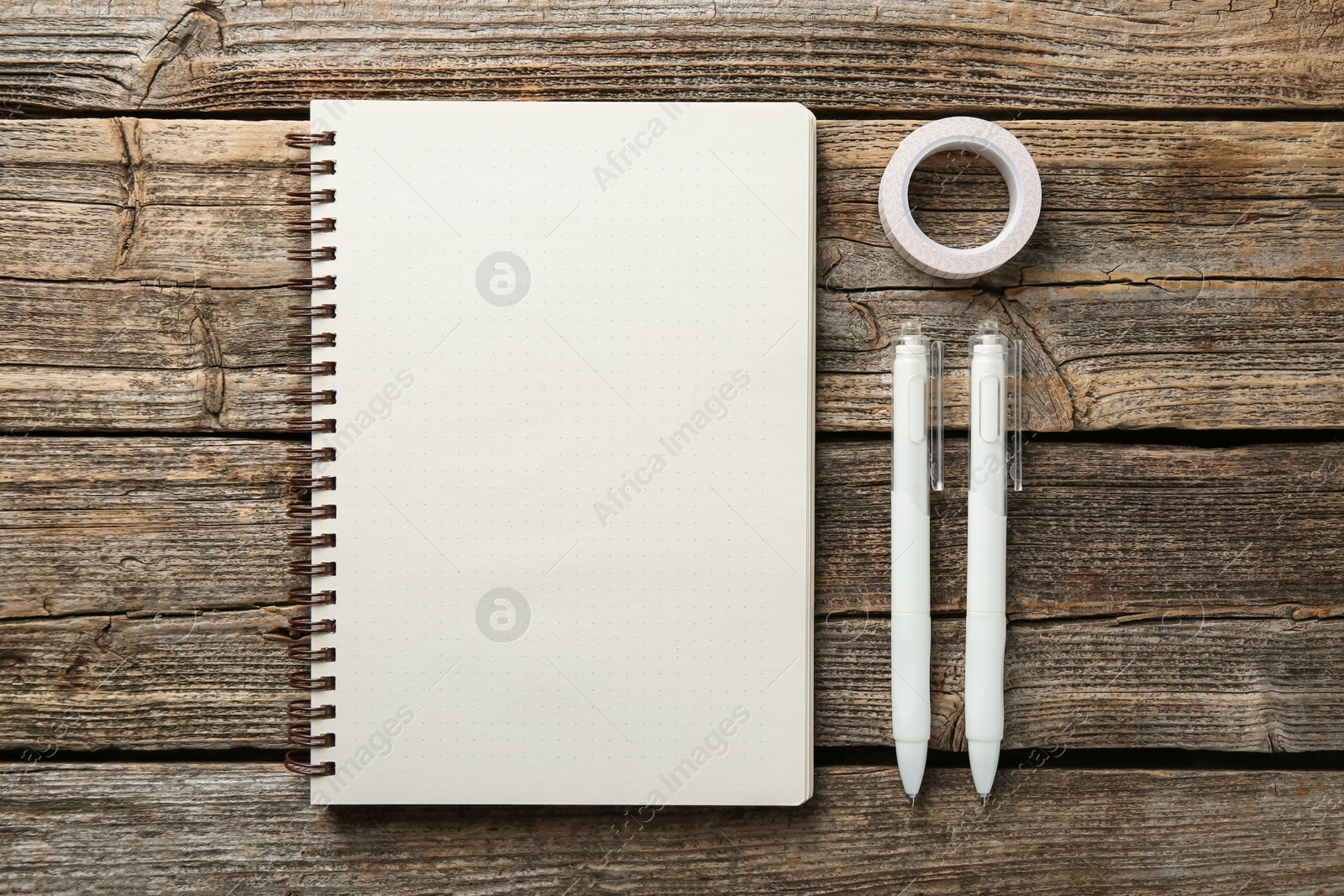 Photo of Open blank notebook, tape and pens on wooden table, flat lay