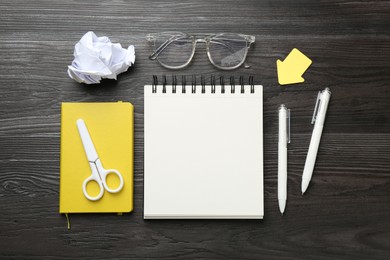Photo of Flat lay composition with open blank notebook on black wooden table