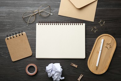 Photo of Flat lay composition with open blank notebook on black wooden table