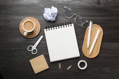 Photo of Flat lay composition with open blank notebook on black wooden table