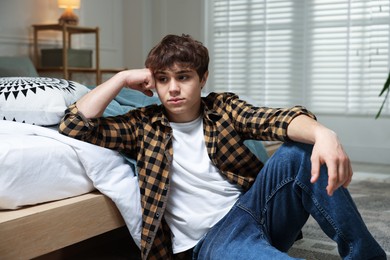Photo of Teen problems. Upset teenage boy on floor at home