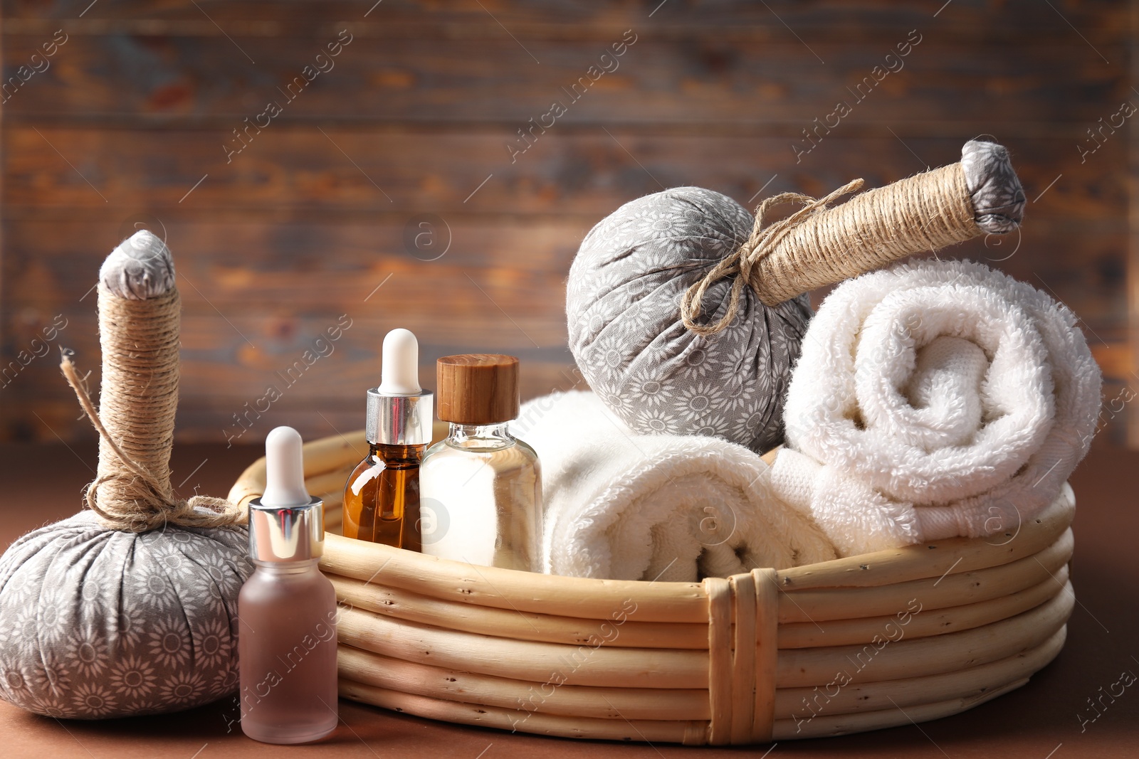 Massage bags, towels and cosmetic products on dark beige table, closeup. Spa composition Photo of Massage bags, towels and cosmetic products on dark beige table, closeup. Spa composition