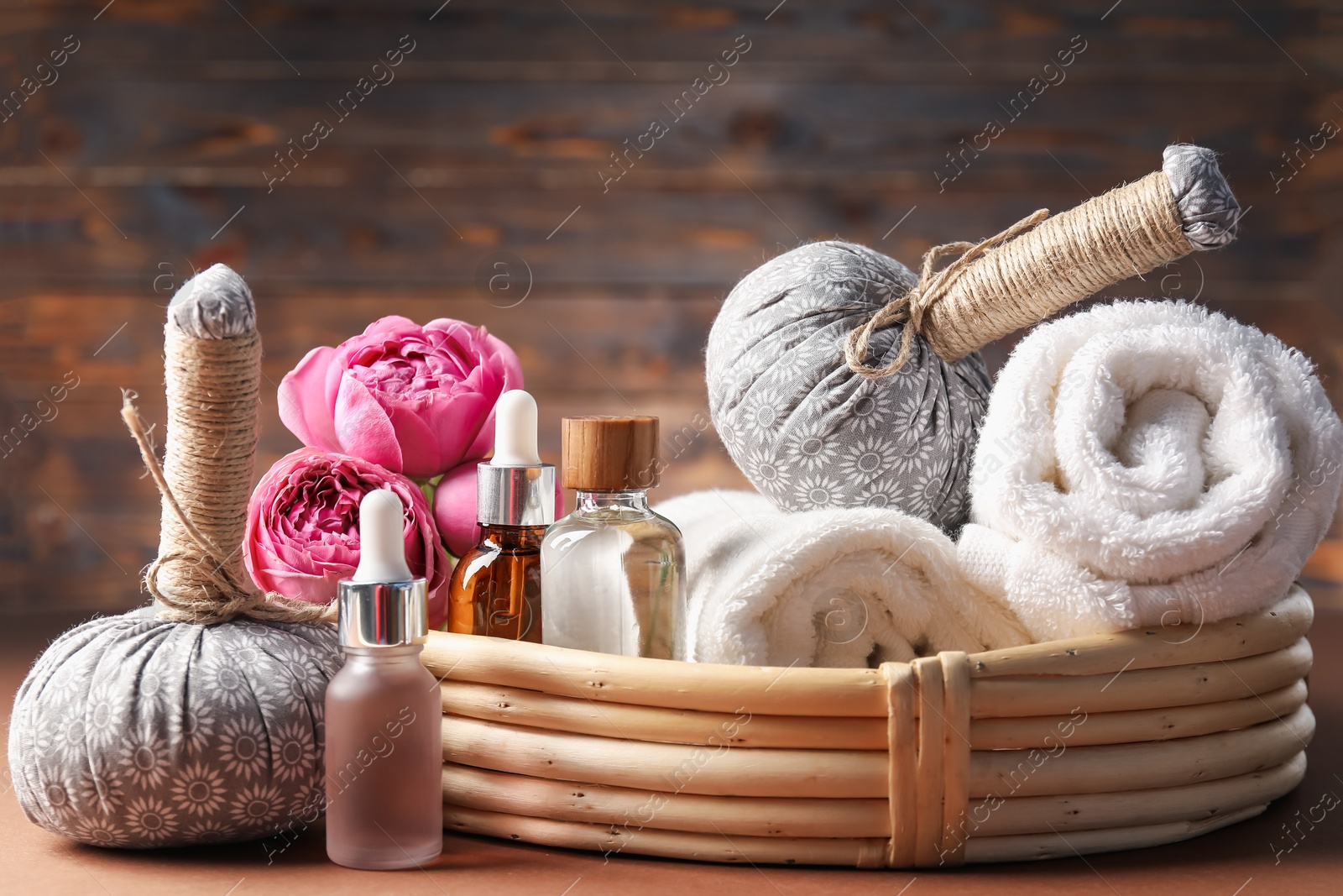 Massage bags, towels, cosmetic products and peony flowers on dark beige table, closeup. Spa composition Photo of Massage bags, towels, cosmetic products and peony flowers on dark beige table, closeup. Spa composition