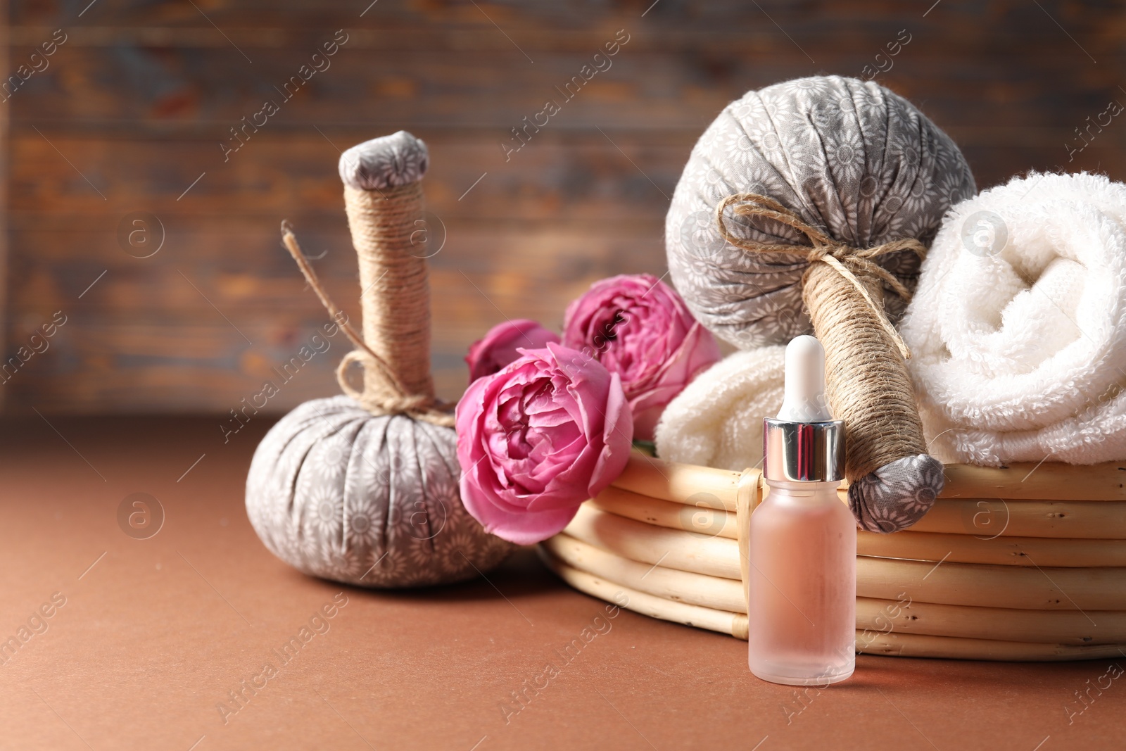Spa composition. Massage bags, towels, cosmetic product and peony flowers on dark beige table, closeup. Space for text Photo of Spa composition. Massage bags, towels, cosmetic product and peony flowers on dark beige table, closeup. Space for text