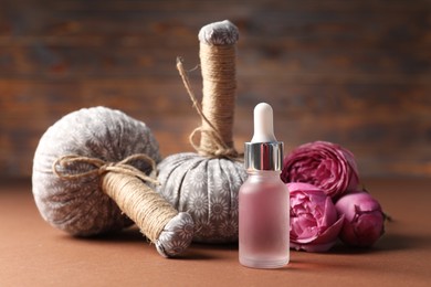 Photo of Massage bags, cosmetic product and peony flowers on dark beige table, closeup. Spa composition
