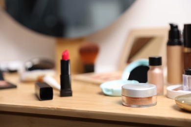 Photo of Different makeup products on wooden vanity indoors, closeup
