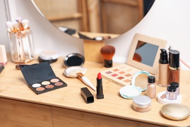 Photo of Different makeup products on wooden vanity indoors, closeup