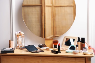 Photo of Different makeup products on wooden vanity indoors