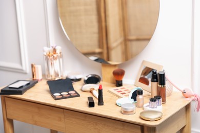 Photo of Different makeup products on wooden vanity indoors