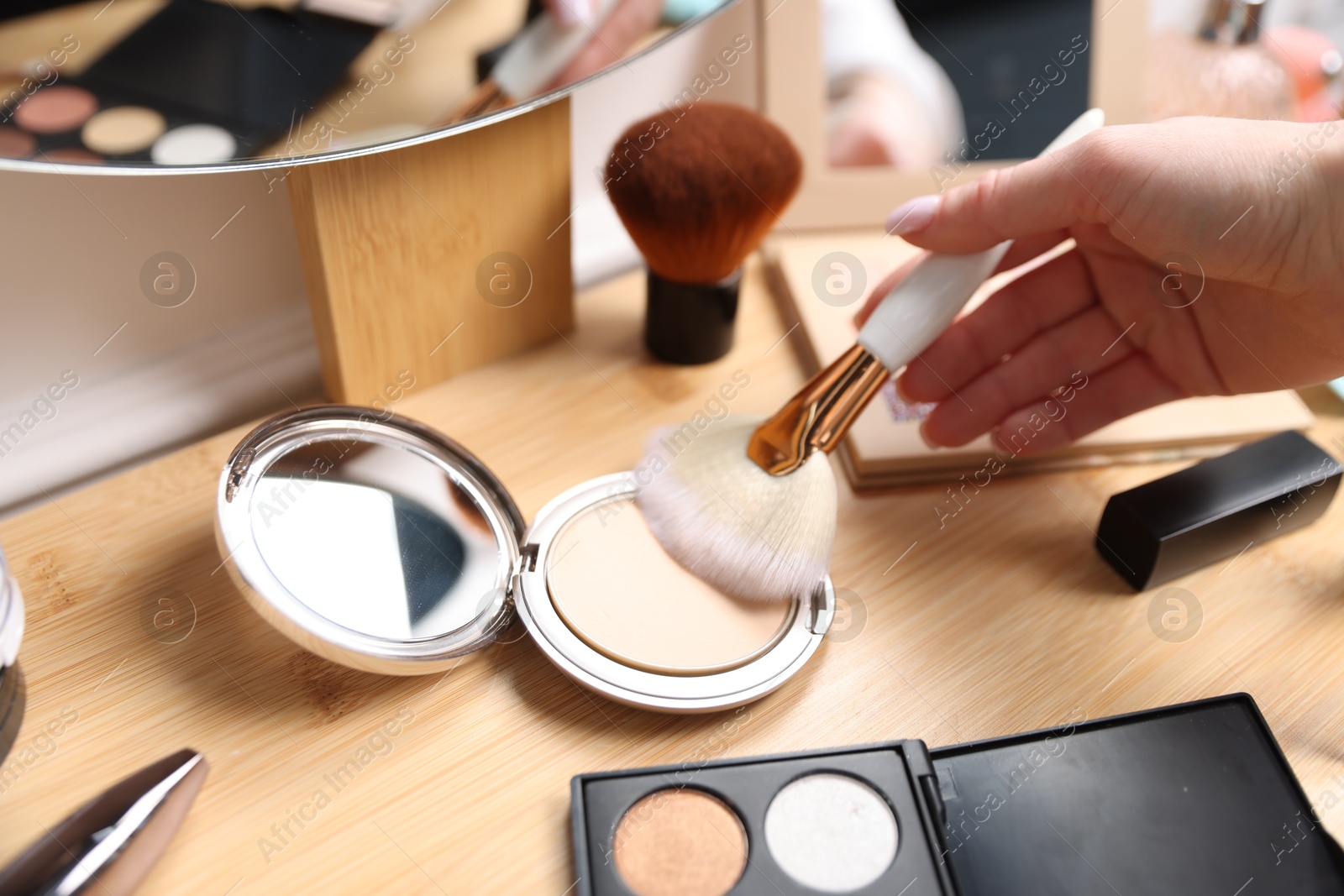 Woman with brush and powder at wooden vanity indoors, closeup Photo of Woman with brush and powder at wooden vanity indoors, closeup