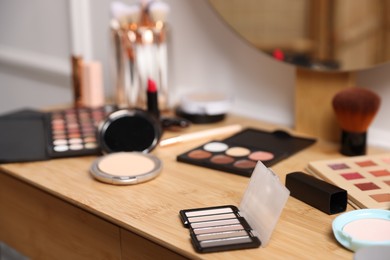 Photo of Different makeup products on wooden vanity indoors, closeup