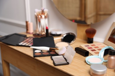 Photo of Different makeup products on wooden vanity indoors, closeup