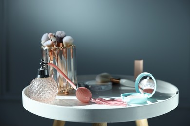 Photo of Different makeup products on white table against grey background, closeup