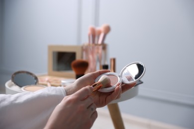 Photo of Woman with brush and powder at table indoors, closeup