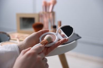 Photo of Woman with brush and powder at table indoors, closeup