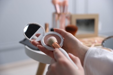 Photo of Woman with brush and powder at table indoors, closeup