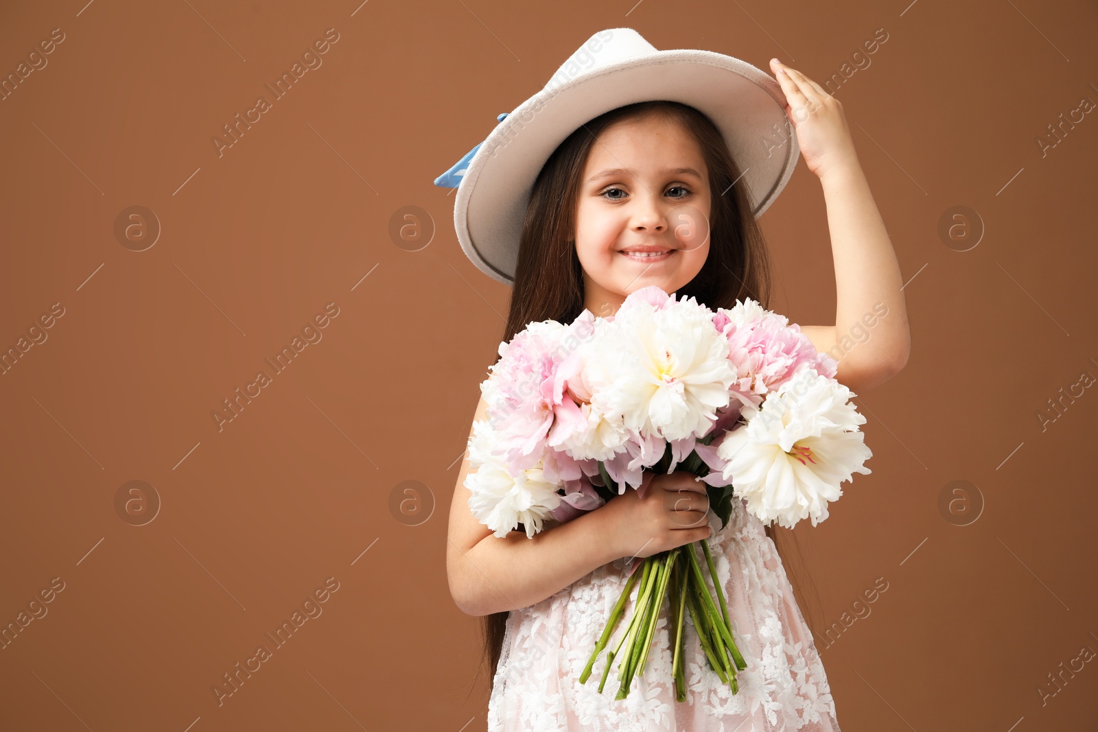Cute little girl with bouquet of beautiful peonies on brown background, space for text Photo of Cute little girl with bouquet of beautiful peonies on brown background, space for text