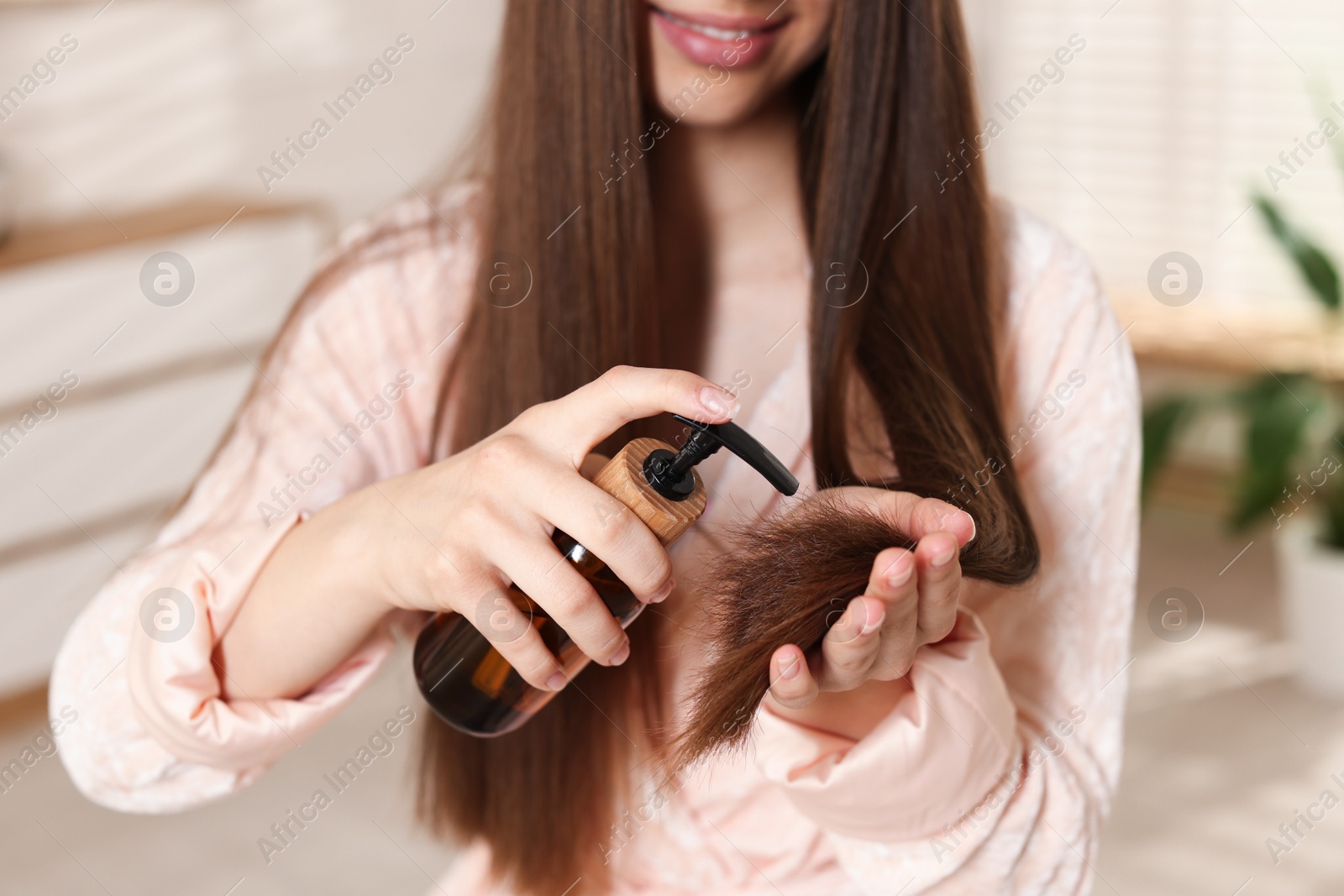 Smiling teenage girl applying cosmetic product onto her hair at home, closeup Photo of Smiling teenage girl applying cosmetic product onto her hair at home, closeup
