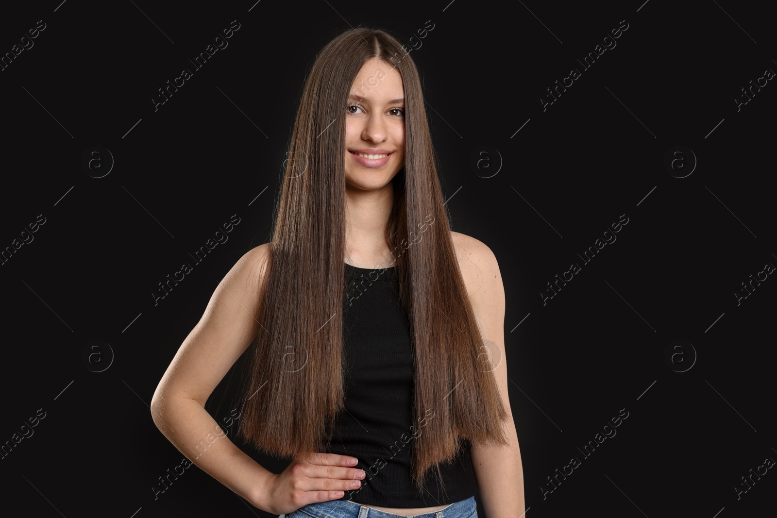 Portrait of smiling teenage girl with healthy long hair on black background Photo of Portrait of smiling teenage girl with healthy long hair on black background