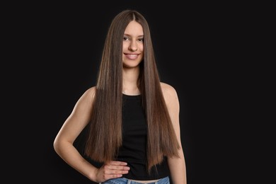 Photo of Portrait of smiling teenage girl with healthy long hair on black background