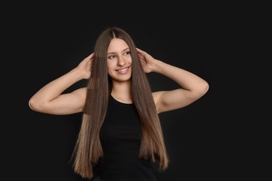 Photo of Portrait of smiling teenage girl with healthy long hair on black background