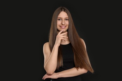 Photo of Portrait of smiling teenage girl with healthy long hair on black background