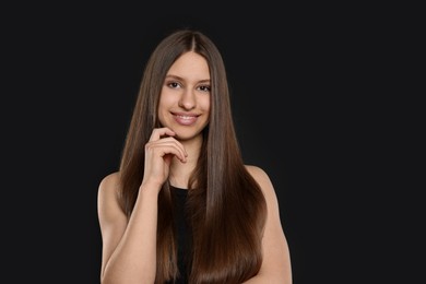 Photo of Portrait of smiling teenage girl with healthy long hair on black background