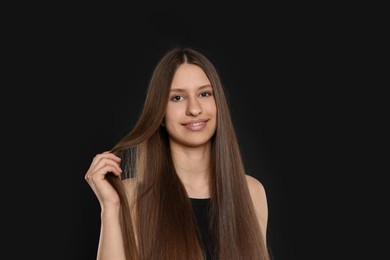 Photo of Portrait of smiling teenage girl with healthy long hair on black background