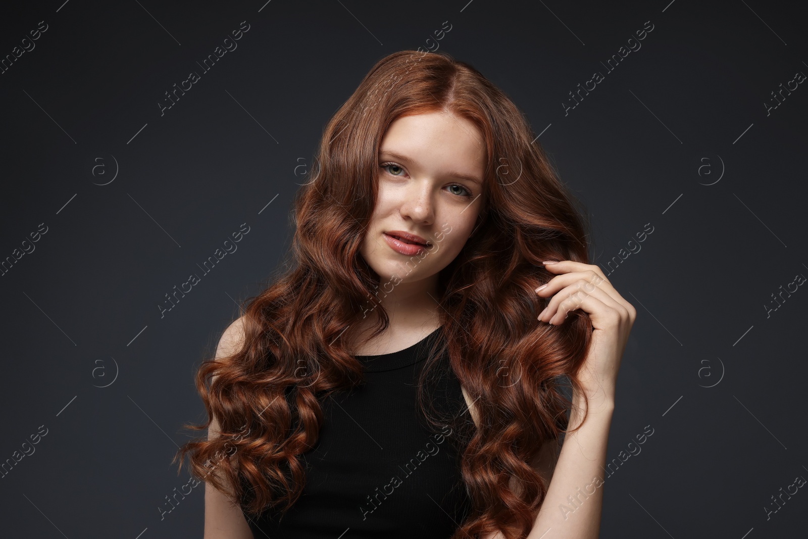 Portrait of beautiful teenage girl with healthy wavy hair on dark grey background Photo of Portrait of beautiful teenage girl with healthy wavy hair on dark grey background