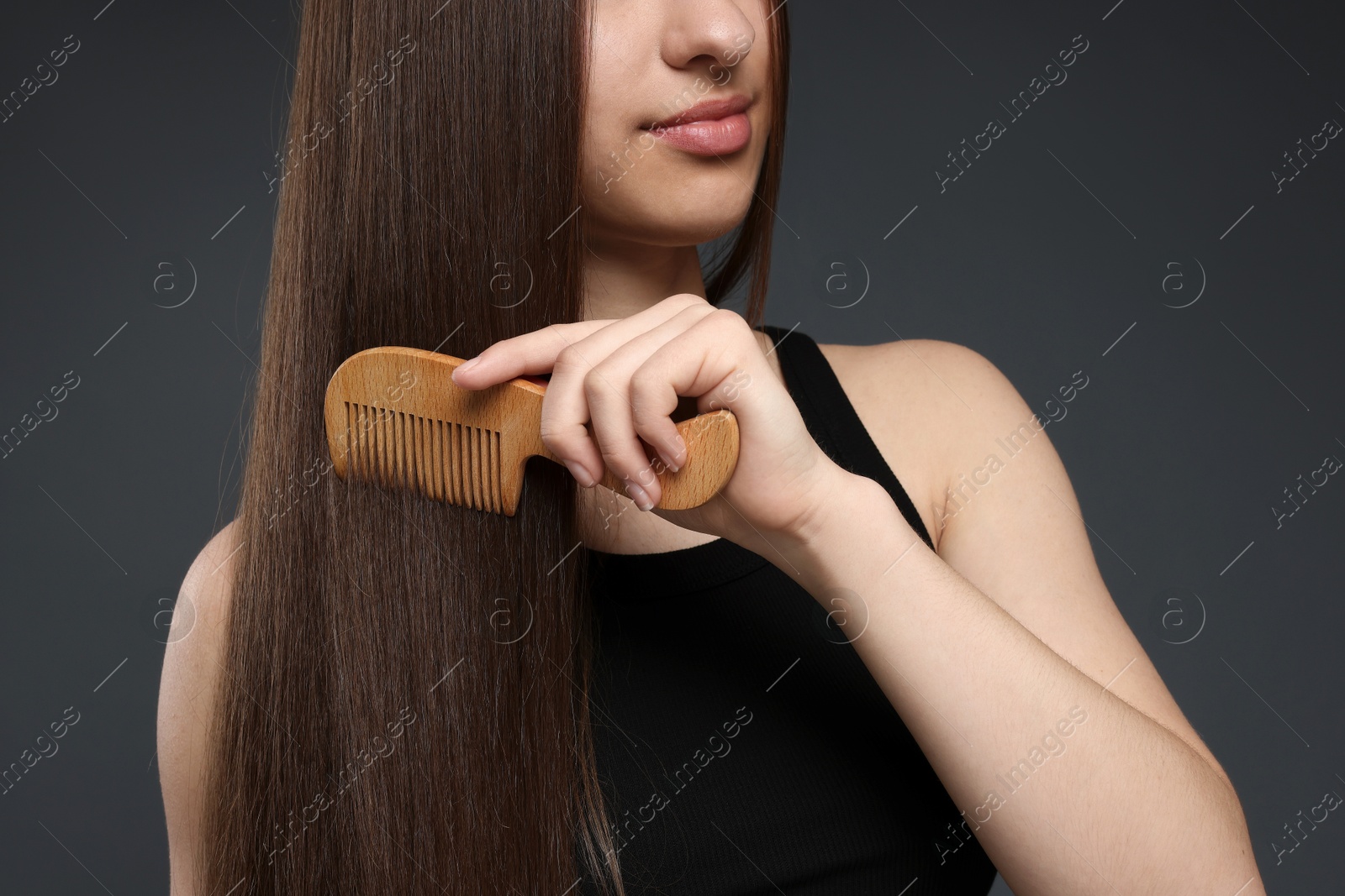Teenage girl brushing her healthy long hair on dark grey background, closeup Photo of Teenage girl brushing her healthy long hair on dark grey background, closeup