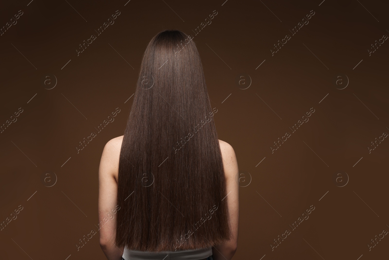 Teenage girl with healthy long hair on brown background, back view Photo of Teenage girl with healthy long hair on brown background, back view
