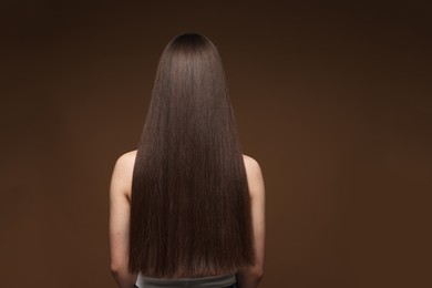 Photo of Teenage girl with healthy long hair on brown background, back view