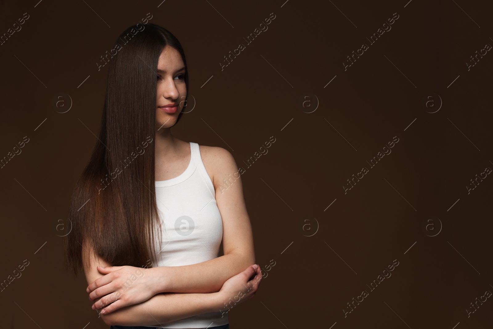 Beautiful teenage girl with healthy long hair on brown background. Space for text Photo of Beautiful teenage girl with healthy long hair on brown background. Space for text