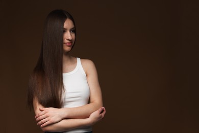 Photo of Beautiful teenage girl with healthy long hair on brown background. Space for text
