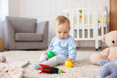 Photo of Cute little baby playing with toys in room