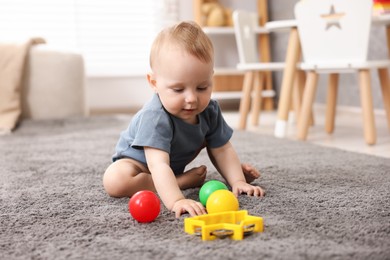 Photo of Cute little baby playing with toys in room