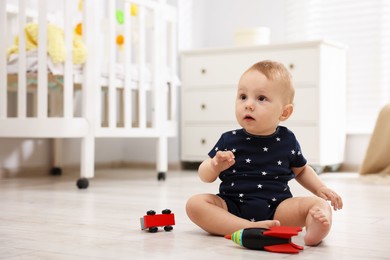 Photo of Cute little baby playing with toys in room, space for text