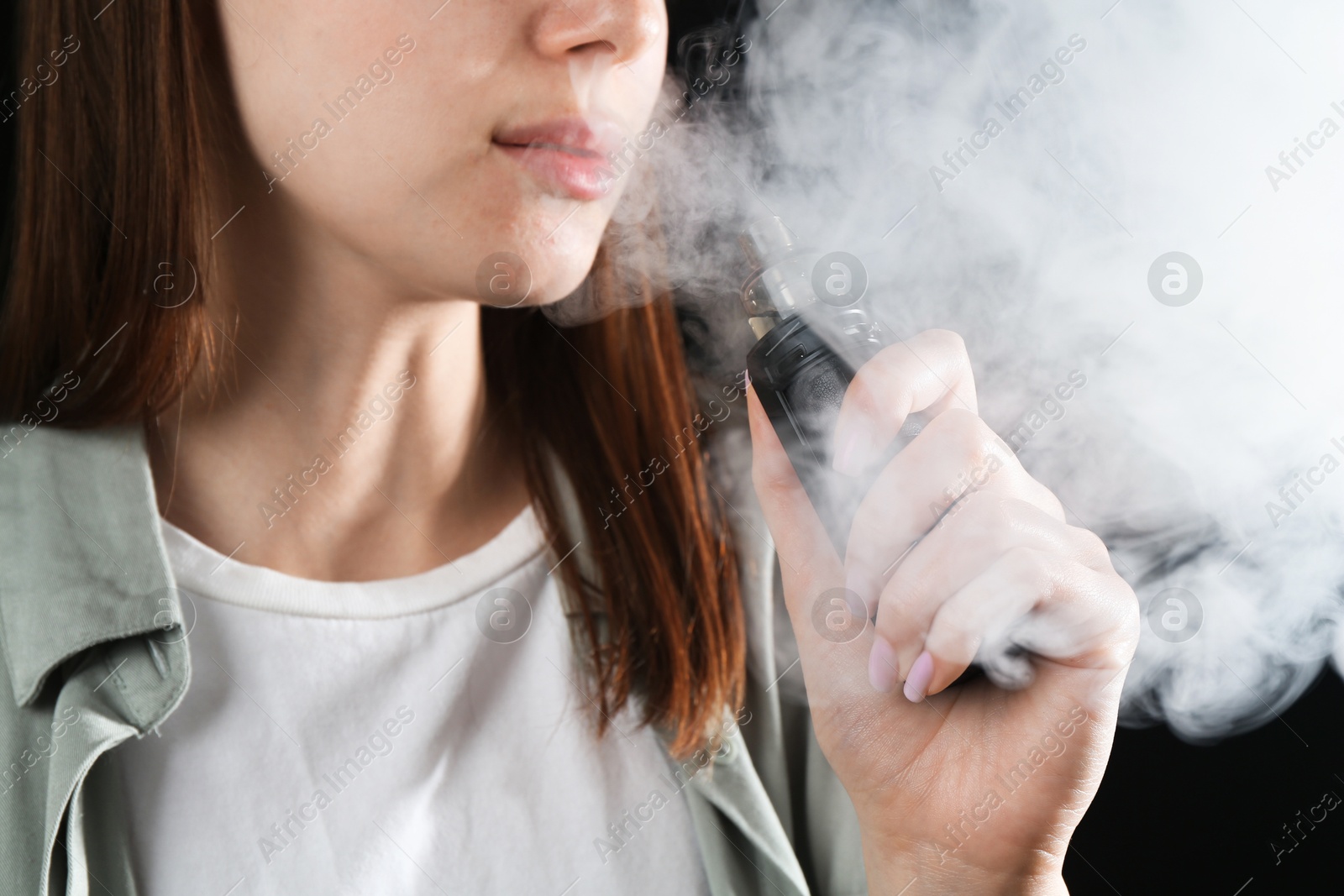 Woman using electronic smoking device on black background, closeup Photo of Woman using electronic smoking device on black background, closeup
