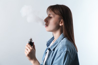 Photo of Woman using electronic smoking device on light grey background
