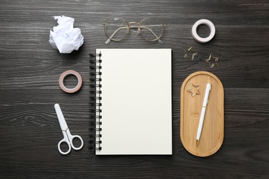 Photo of Flat lay composition with open blank notebook on black wooden table