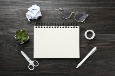 Photo of Flat lay composition with open blank notebook on black wooden table