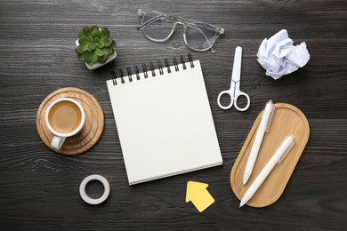 Photo of Flat lay composition with open blank notebook on black wooden table