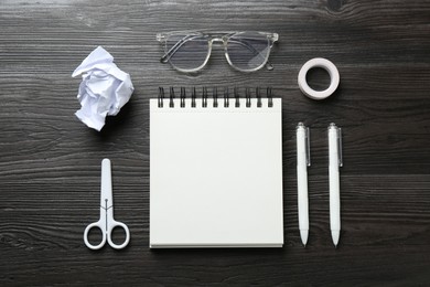 Photo of Flat lay composition with open blank notebook on black wooden table