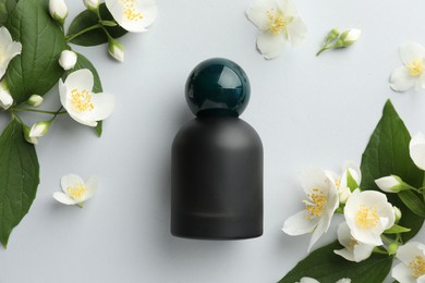 Photo of Bottle of perfume and jasmine flowers on light background, flat lay